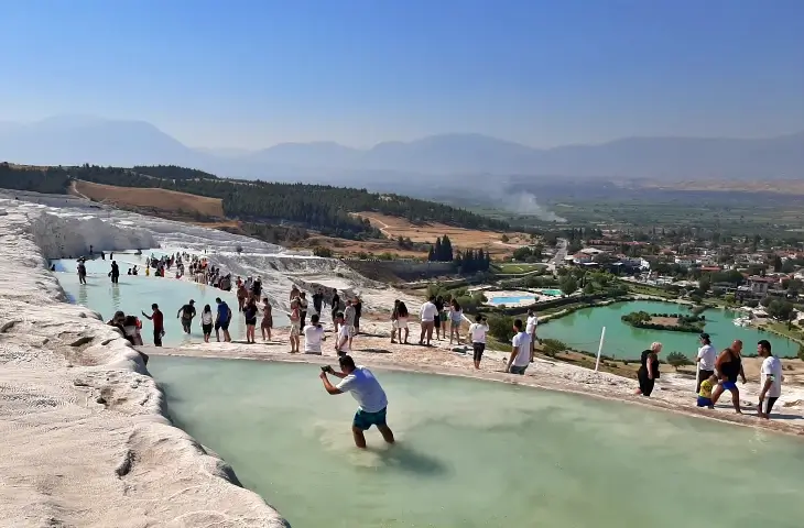 Pamukkale travertenlerinde yürüyen ziyaretçiler ve traverten havuzları Denizli